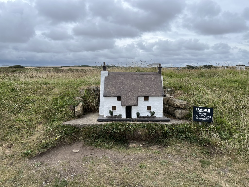 A model house photographed against a busy sky, foreground, and background